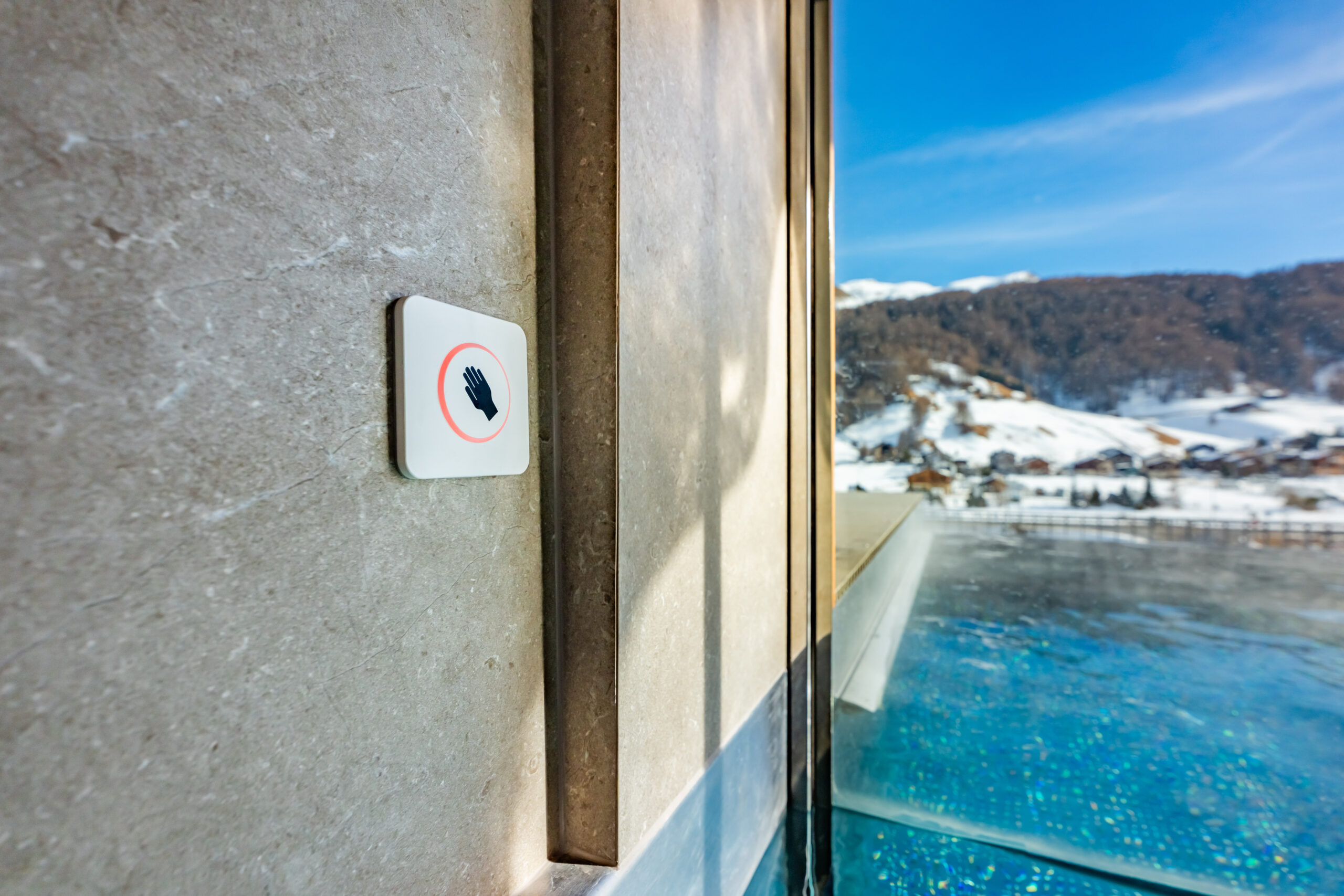 Design Infinity Pool v alpském resortu — piezoelektrické ovládací pole na stěně bazénu s panoramatickým výhledem na zasněžené hory v zimě