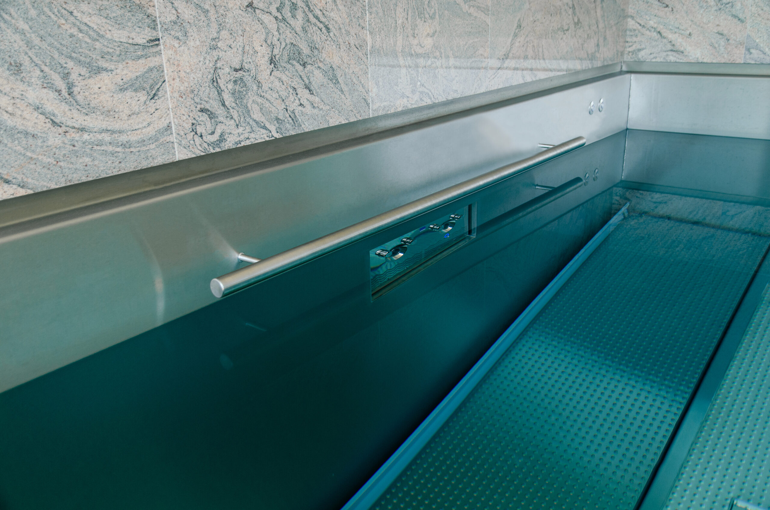 A close-up view of the IMAGINOX counter-current system with stainless steel handrails and controls around the edge of the pool.